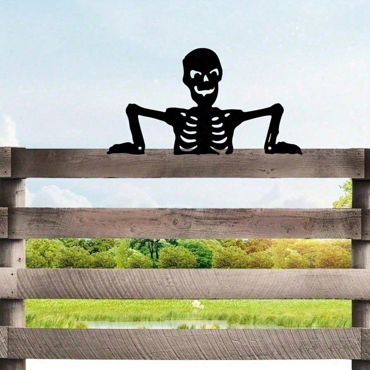Black skeleton silhouette peeking over a wooden fence rail