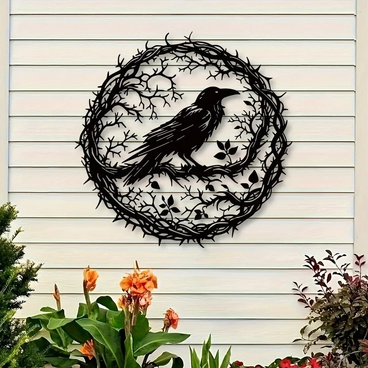 Black crow wreath wall art on light siding above flowers