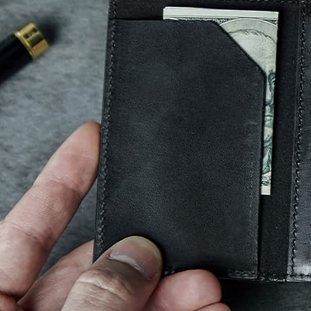 Slim black wallet opened to the inner flap, with a folded bill tucked behind it