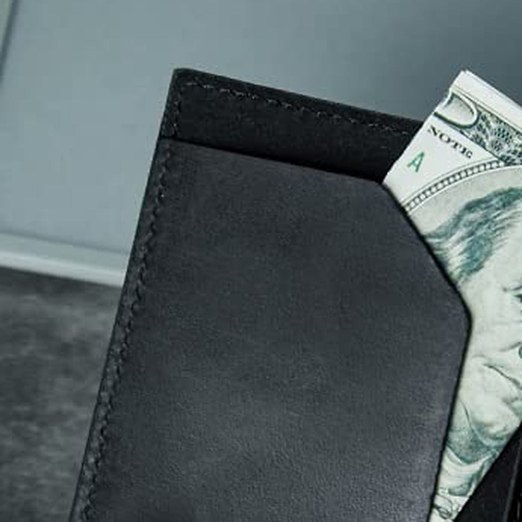 Folded cash tucked into the slim wallet's inner bill pocket